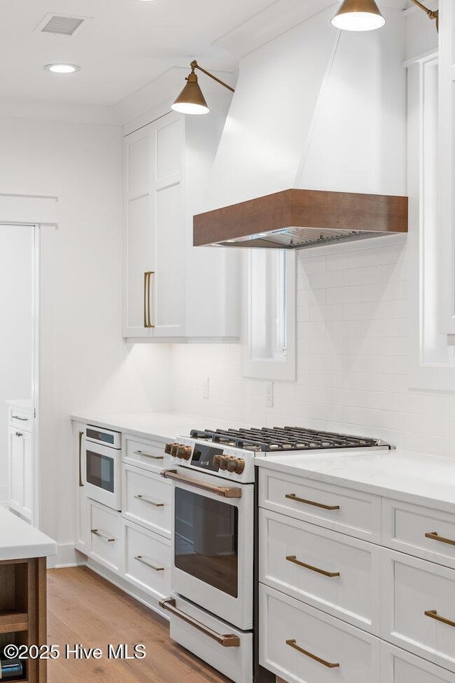 3404 Eagle Crest Dr SW, Supply, NC 28462 - kitchen with high end stove, premium range hood, decorative backsplash, light wood-type flooring, and light countertops