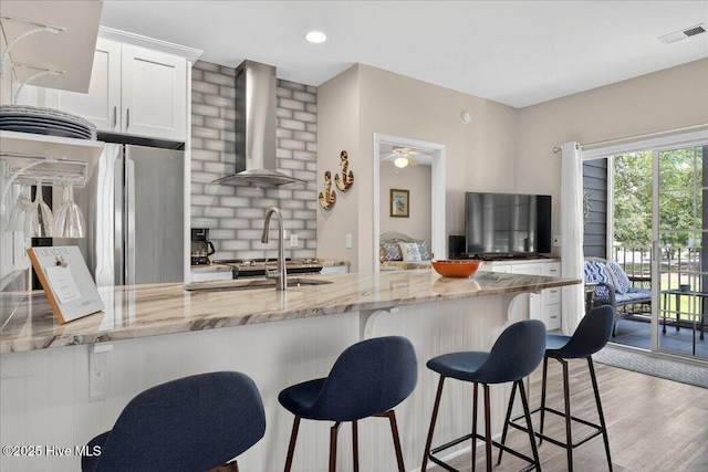 145 Royal Poste Rd # 3110, Sunset Beach, NC 28468 - kitchen with wall chimney range hood, light stone countertops, white cabinetry, and a kitchen bar