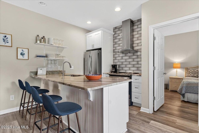 145 Royal Poste Rd # 3110, Sunset Beach, NC 28468 - kitchen featuring wall chimney range hood, stainless steel appliances, open shelves, a kitchen breakfast bar, and wood finished floors