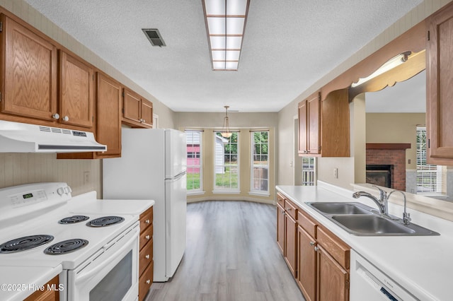 26 Combine Ln SE, Leland, NC 28451 - kitchen with under cabinet range hood, white appliances, light countertops, light wood-style flooring, and brown cabinetry