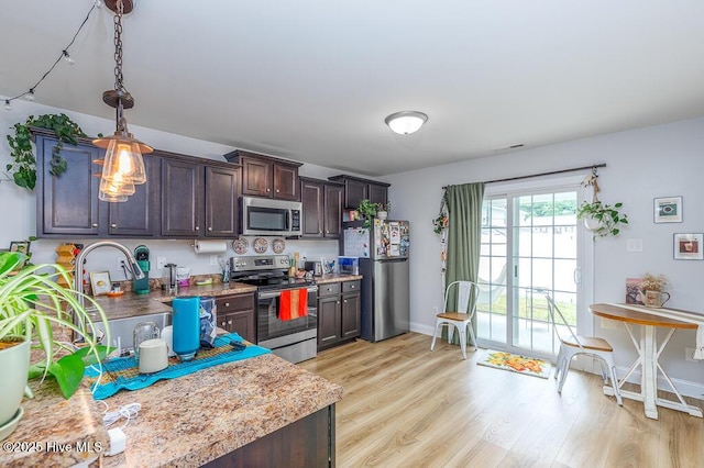 110 Meadow Way, Havelock, NC 28532 - kitchen featuring appliances with stainless steel finishes, light wood-style floors, dark brown cabinets, hanging light fixtures, and light countertops