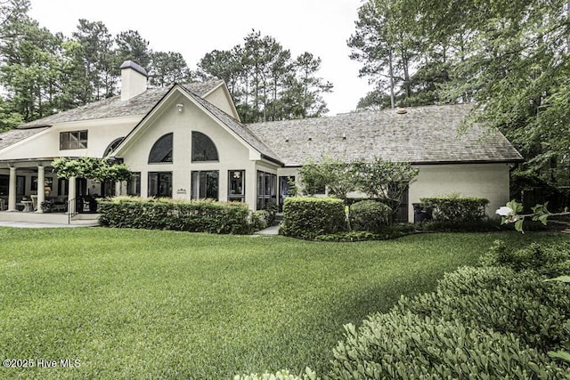129 Steeplechase Rd, Rocky Mount, NC 27804 - back of house featuring stucco siding, a lawn, a chimney, and a patio