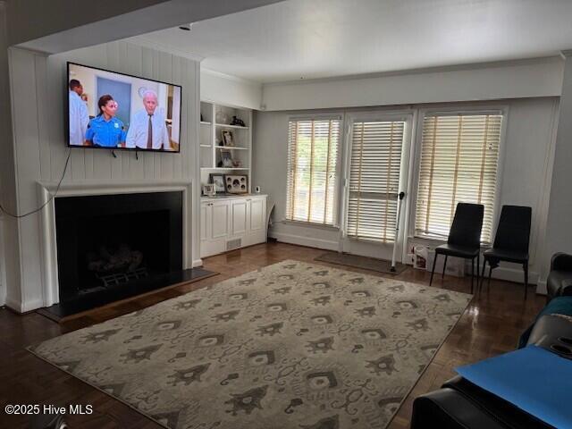 621 W Hayes St, Ahoskie, NC 27910 - living area featuring a fireplace with raised hearth, built in features, wood finished floors, and crown molding