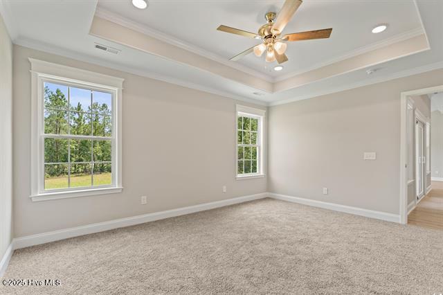 414 Laurel Ct NW, Calabash, NC 28467 - empty room featuring a raised ceiling, crown molding, plenty of natural light, recessed lighting, and light colored carpet