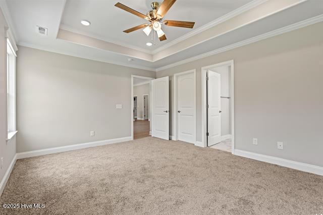 414 Laurel Ct NW, Calabash, NC 28467 - unfurnished bedroom with crown molding, carpet flooring, a tray ceiling, recessed lighting, and ensuite bathroom