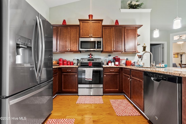 1067 Tideline Dr, Leland, NC 28451 - kitchen featuring appliances with stainless steel finishes, a peninsula, light wood-style floors, vaulted ceiling, and hanging light fixtures
