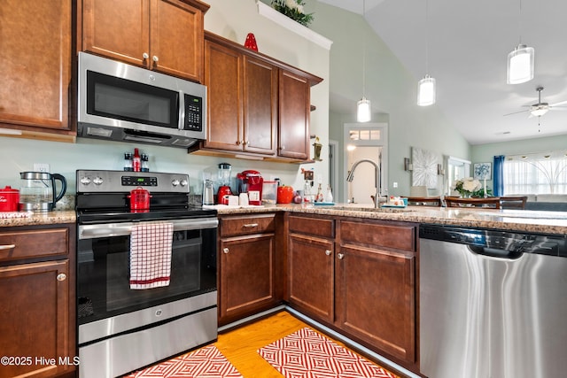 1067 Tideline Dr, Leland, NC 28451 - kitchen with appliances with stainless steel finishes, lofted ceiling, light wood-type flooring, hanging light fixtures, and light stone countertops