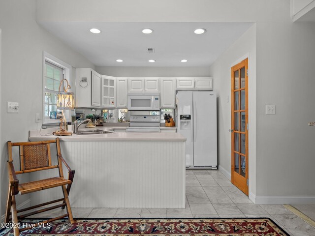 403 Emerald Landing Dr, Emerald Isle, NC 28594 - kitchen with white appliances, a peninsula, light countertops, glass insert cabinets, and white cabinetry