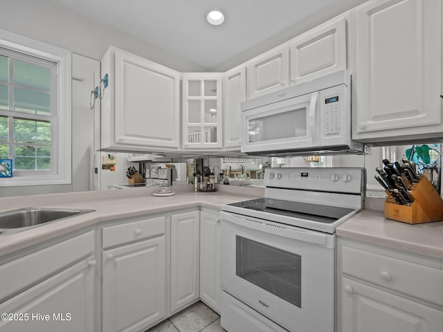 403 Emerald Landing Dr, Emerald Isle, NC 28594 - kitchen featuring white appliances, white cabinetry, light countertops, glass insert cabinets, and light tile patterned floors