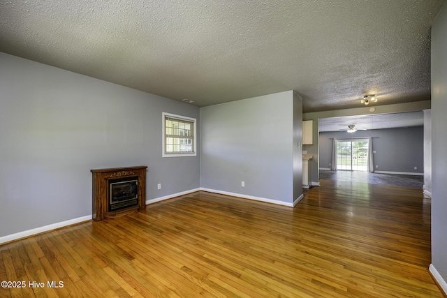 103 Elizabeth St, Havelock, NC 28532 - unfurnished living room with wood-type flooring, a glass covered fireplace, a textured ceiling, and ceiling fan