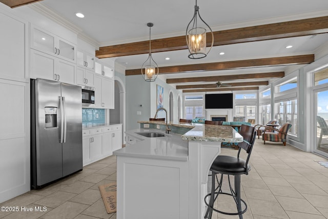 4101 Ocean Dr, Emerald Isle, NC 28594 - kitchen with stainless steel appliances, beam ceiling, arched walkways, a ceiling fan, and white cabinets
