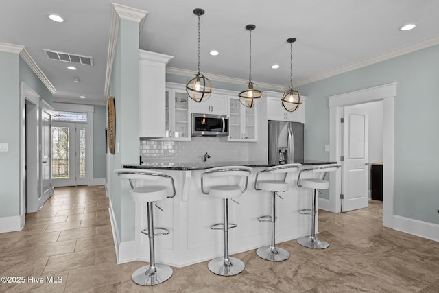 4101 Ocean Dr, Emerald Isle, NC 28594 - kitchen featuring stainless steel appliances, a breakfast bar, backsplash, glass insert cabinets, and crown molding