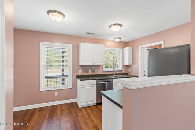 1281 Washington Rd, Southport, NC 28461 - kitchen with appliances with stainless steel finishes, white cabinets, dark wood-type flooring, dark countertops, and a peninsula