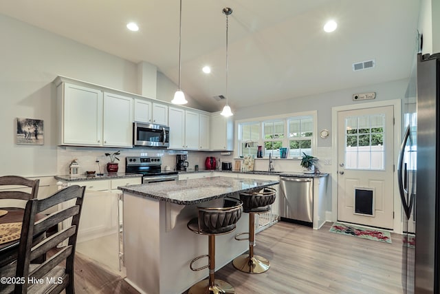 1284 Marsilio Ln SW Unit B, Ocean Isle Beach, NC 28469 - kitchen with appliances with stainless steel finishes, lofted ceiling, light stone countertops, light wood-style floors, and a kitchen island