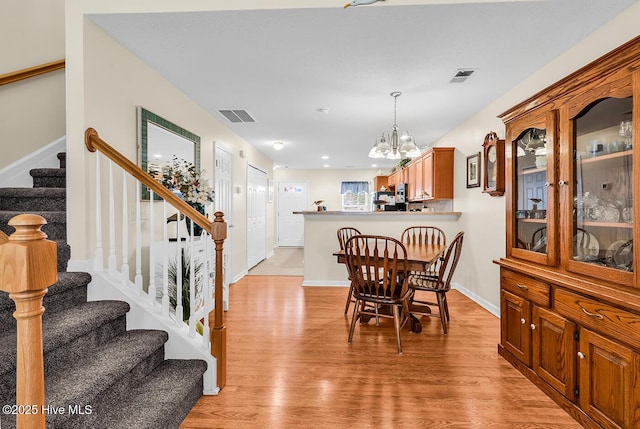 2129 Cass Lake Dr, Calabash, NC 28467 - dining space featuring a chandelier, light wood-type flooring, and stairs