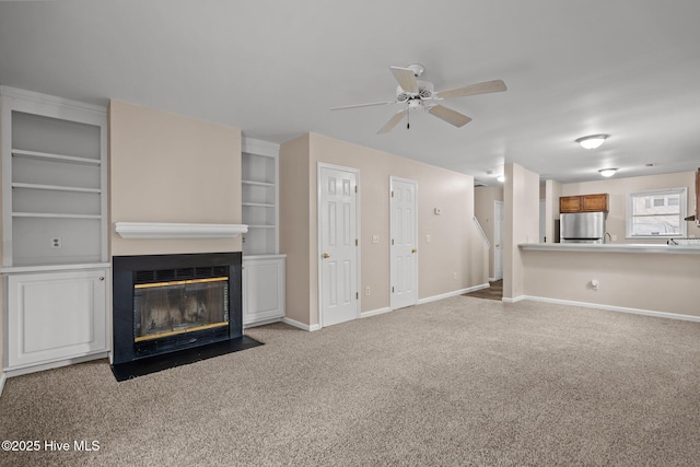 136 Lullwater Dr Unit B, Wilmington, NC 28403 - unfurnished living room with carpet, a ceiling fan, a fireplace with flush hearth, and built in shelves