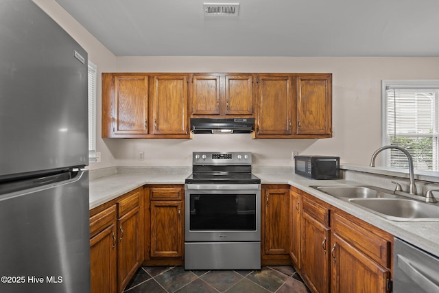 136 Lullwater Dr Unit B, Wilmington, NC 28403 - kitchen featuring stainless steel appliances, under cabinet range hood, light countertops, and brown cabinetry