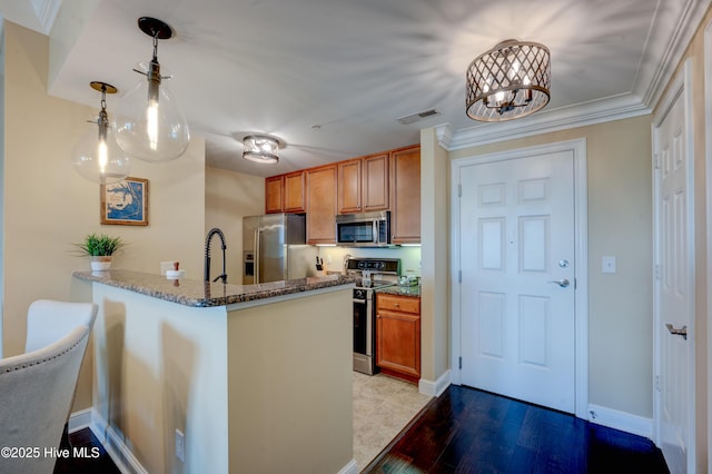 203 Sky Sail Blvd, New Bern, NC 28560 - kitchen featuring appliances with stainless steel finishes, dark stone counters, brown cabinets, a peninsula, and pendant lighting