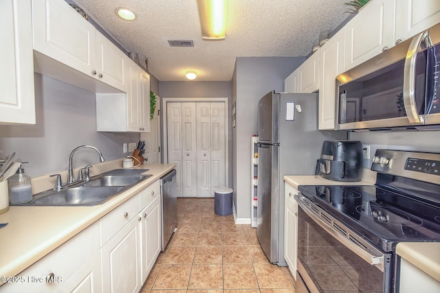 2505 Legend Dr, Wilmington, NC 28405 - kitchen featuring appliances with stainless steel finishes, white cabinets, light countertops, a textured ceiling, and light tile patterned floors