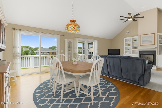 512 Shell Dr, Kure Beach, NC 28449 - dining area featuring light wood-type flooring, a ceiling fan, high vaulted ceiling, and a fireplace