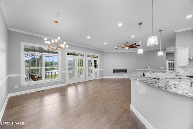 376 Red Fox Run Dr, Wallace, NC 28466 - kitchen with a ceiling fan, a glass covered fireplace, open floor plan, white cabinets, and ornamental molding