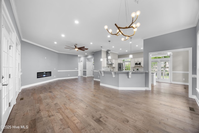 376 Red Fox Run Dr, Wallace, NC 28466 - unfurnished living room featuring ornamental molding, a chandelier, ceiling fan, wood finished floors, and a glass covered fireplace