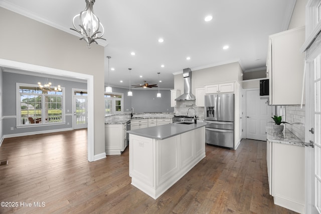 376 Red Fox Run Dr, Wallace, NC 28466 - kitchen featuring stainless steel refrigerator with ice dispenser, a chandelier, wall chimney exhaust hood, an island with sink, and backsplash