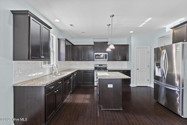 109 Creek End Ct, Swansboro, NC 28584 - kitchen with appliances with stainless steel finishes, dark brown cabinetry, a center island, light stone countertops, and decorative backsplash