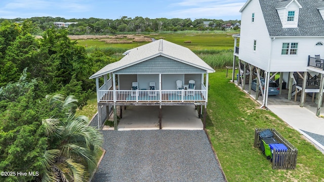 316 E Dolphin Dr, Oak Island, NC 28465 - coastal home featuring a carport, concrete driveway, a front lawn, and a porch