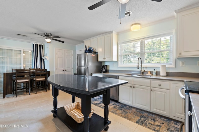 316 E Dolphin Dr, Oak Island, NC 28465 - kitchen featuring appliances with stainless steel finishes, a ceiling fan, white cabinets, and a textured ceiling