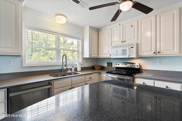 316 E Dolphin Dr, Oak Island, NC 28465 - kitchen with stainless steel appliances, ceiling fan, a textured ceiling, white cabinets, and crown molding