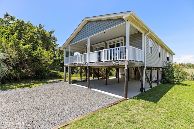 316 E Dolphin Dr, Oak Island, NC 28465 - beach home featuring driveway, a carport, a front lawn, and covered porch