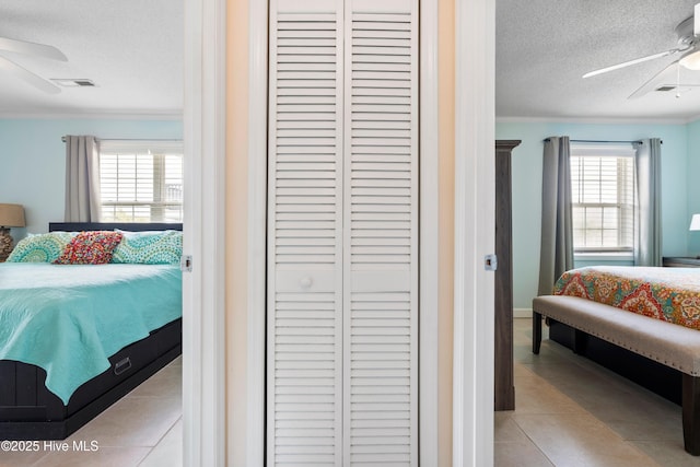 316 E Dolphin Dr, Oak Island, NC 28465 - bedroom with a textured ceiling, crown molding, a closet, light tile patterned floors, and ceiling fan