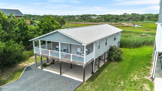 316 E Dolphin Dr, Oak Island, NC 28465 - rear view of property with gravel driveway, a lawn, a deck, and a shingled roof