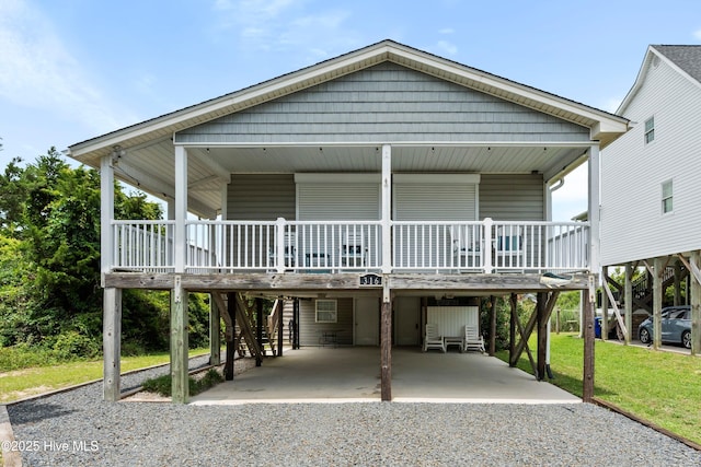 316 E Dolphin Dr, Oak Island, NC 28465 - raised beach house with a carport, gravel driveway, a porch, and a front yard
