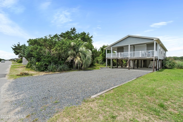316 E Dolphin Dr, Oak Island, NC 28465 - raised beach house featuring a carport, gravel driveway, and a front yard