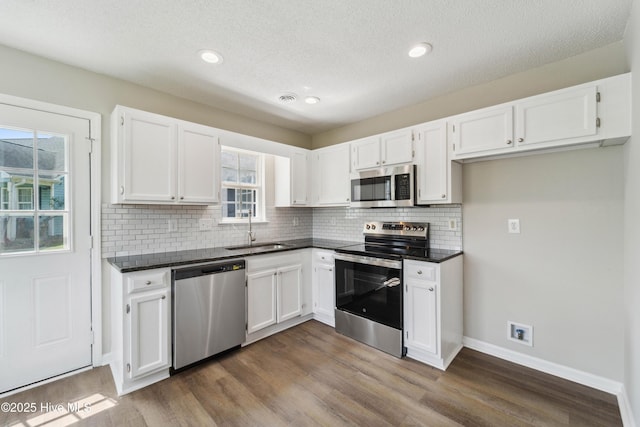 802 Mayfield Ct, Wilmington, NC 28411 - kitchen featuring appliances with stainless steel finishes, dark countertops, white cabinetry, backsplash, and dark wood-style flooring