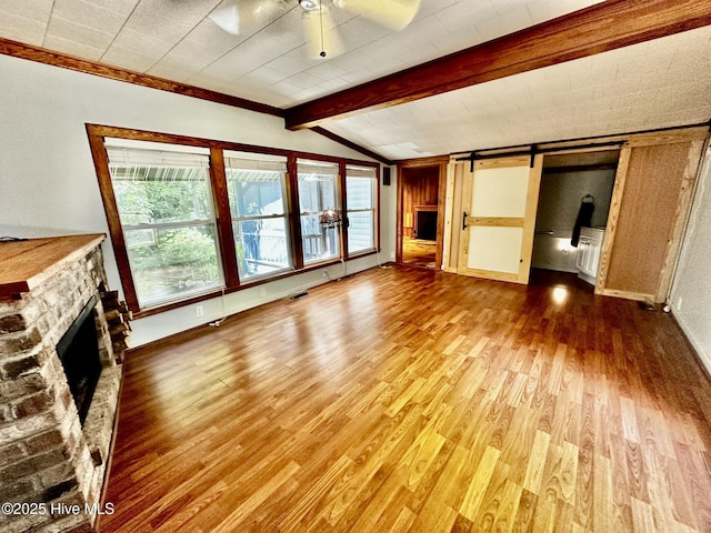 9550 NC-171, Williamston, NC 27892 - unfurnished living room featuring wood finished floors, a fireplace, ceiling fan, and a barn door