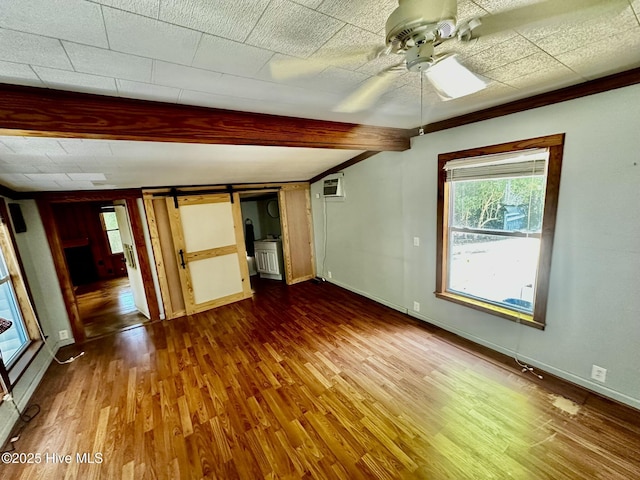 9550 NC-171, Williamston, NC 27892 - unfurnished bedroom with a barn door, dark wood finished floors, beamed ceiling, a wall mounted AC, and ceiling fan
