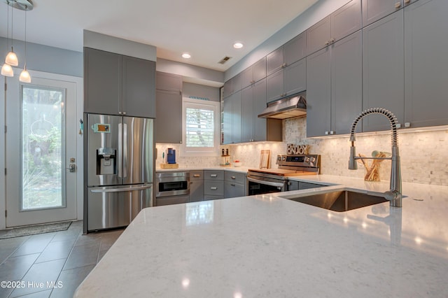 8508 Hammock Dunes Dr, Wilmington, NC 28411 - kitchen with appliances with stainless steel finishes, light stone countertops, under cabinet range hood, gray cabinets, and decorative backsplash