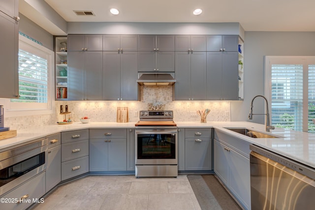 8508 Hammock Dunes Dr, Wilmington, NC 28411 - kitchen with stainless steel appliances, open shelves, gray cabinetry, extractor fan, and light countertops