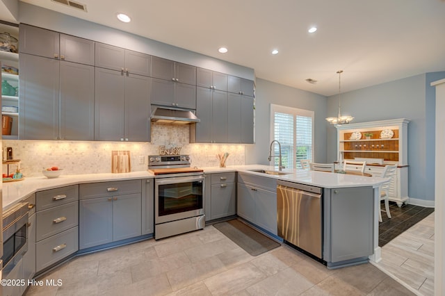 8508 Hammock Dunes Dr, Wilmington, NC 28411 - kitchen with appliances with stainless steel finishes, gray cabinets, a chandelier, a peninsula, and decorative backsplash