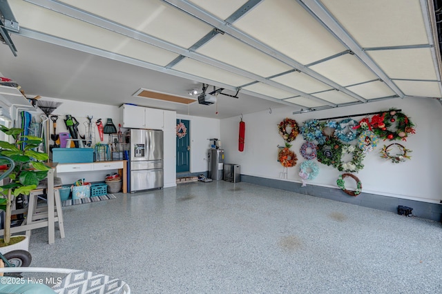 8508 Hammock Dunes Dr, Wilmington, NC 28411 - garage featuring stainless steel fridge with ice dispenser, a garage door opener, and electric water heater