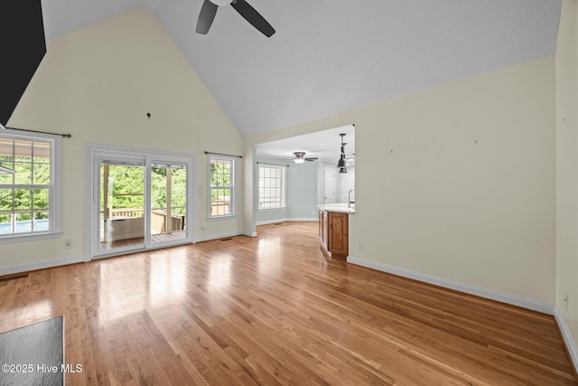 2639 Plumosa Dr, Grimesland, NC 27837 - unfurnished living room featuring a ceiling fan, high vaulted ceiling, healthy amount of natural light, and light wood-style flooring