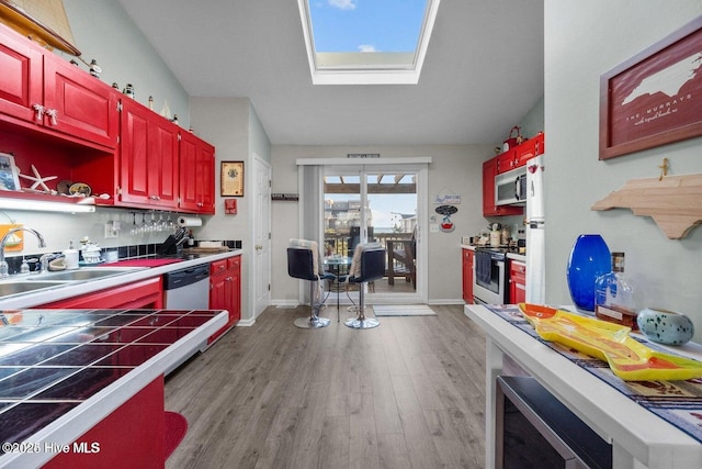 1785 New River Inlet Rd Unit 2, North Topsail Beach, NC 28460 - kitchen with appliances with stainless steel finishes, wood finished floors, tile counters, a skylight, and open shelves