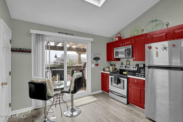1785 New River Inlet Rd Unit 2, North Topsail Beach, NC 28460 - kitchen with stainless steel appliances, vaulted ceiling, light wood finished floors, reddish brown cabinets, and light countertops