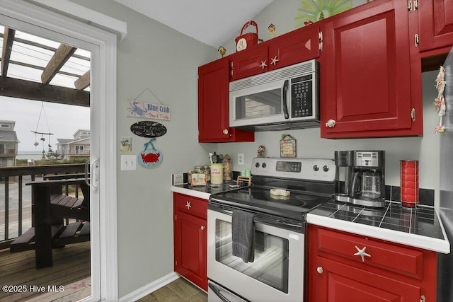 1785 New River Inlet Rd Unit 2, North Topsail Beach, NC 28460 - kitchen with appliances with stainless steel finishes, plenty of natural light, wood finished floors, tile counters, and vaulted ceiling