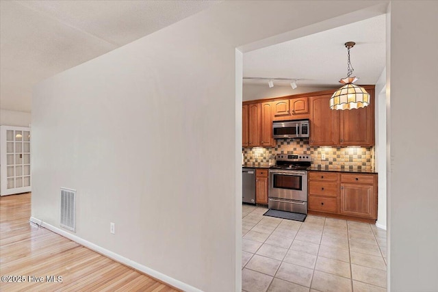 120 Shagbark Ct, Seven Lakes, NC 27376 - kitchen with stainless steel appliances, dark countertops, backsplash, pendant lighting, and brown cabinetry