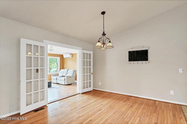 120 Shagbark Ct, Seven Lakes, NC 27376 - empty room featuring a chandelier, hardwood / wood-style floors, french doors, and a wall mounted AC