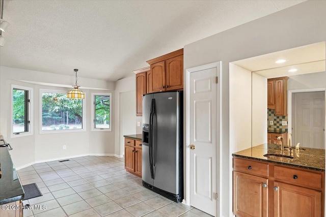 120 Shagbark Ct, Seven Lakes, NC 27376 - kitchen featuring black fridge with ice dispenser, brown cabinetry, dark stone countertops, decorative backsplash, and light tile patterned floors